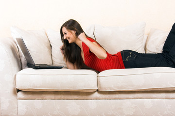 young woman on a lounge with laptop is cheering