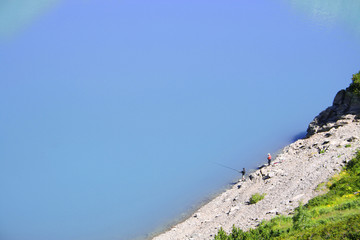Men fishing in the lake in a mountain landscape