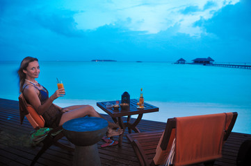 woman having a tropical cocktail at sunset