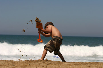 petit garçon entrain de jouer sur la plage avec une pelle