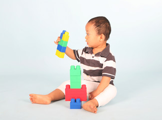 Cute toddler playing with his blocks shot over blue background