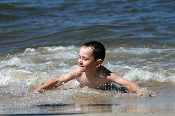 4 years old boy playing in the sea