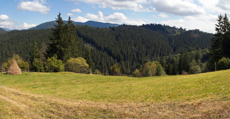 Summer mountain green meadow with stack of hay