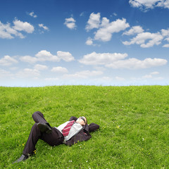 businessman sleeping on green grass