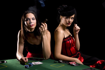 Two attractive woman playing poker and smoking cigarettes