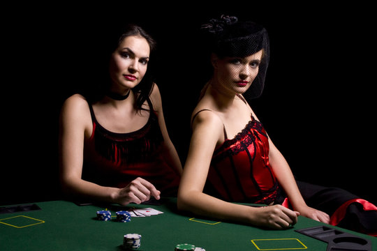 Two attractive woman playing poker and at the casino