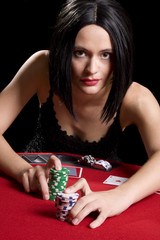 Determined attractive brunette playing cards at a red poker