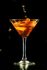 alcohol splash in martini glass on black background