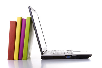 a laptop next to a stack of colorful books