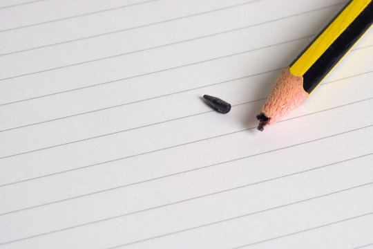 Pencil with a broken tip on a writing pad..