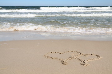 Fototapeta na wymiar Two hearts drawn in sand on a beach