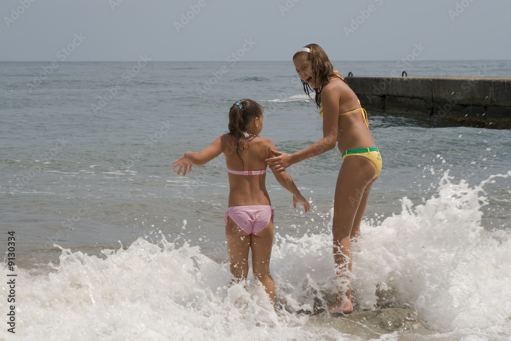 Wall mural two girls of teenager make merry during a gale at the  seaside