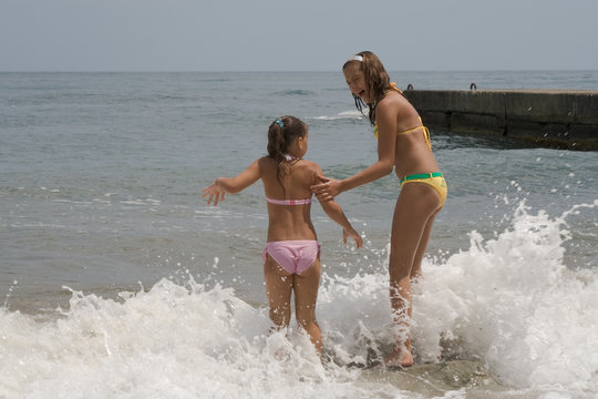 two girls of teenager make merry during a gale at the  seaside