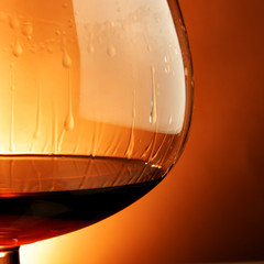 Snifter glass of cognac close-up over yellow background