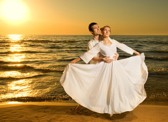 Young couple in love near the ocean at sunset