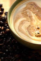 kaffee mit cremigem schaum und kaffeebohnen