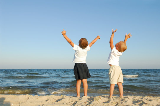 Freedom. Two boys on the beach with arms raied
