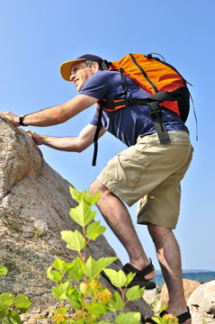 Middle Aged Man With Backpack Climbing A Rock