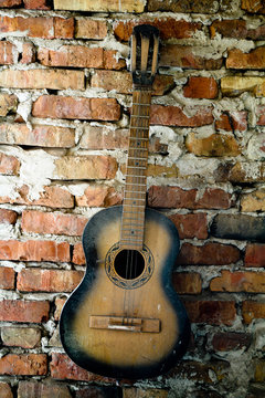 an old guitar on the brick wall © Mykola Velychko