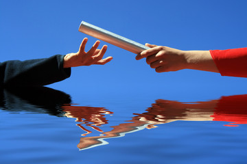 hands passing the batton against blue sky