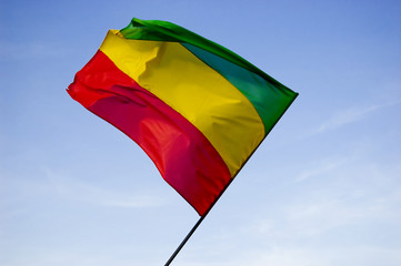 Red, yellow, green reggae flag over blue sky