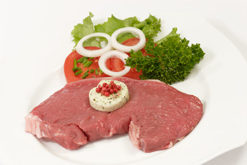 Fototapeta premium Rohes Rindersteak mit Garnierung auf hellem Hintergrund