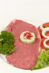 Rohes Rindersteak mit Garnierung auf hellem Hintergrund