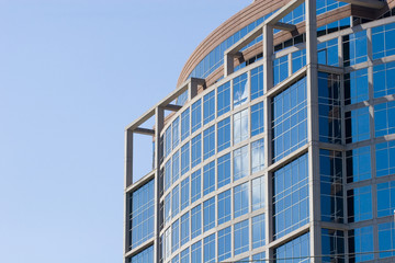 Obraz premium A modern blue glass tower reflecting clouds and sky