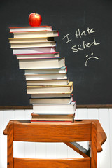 Stack of books on an old school desk with blackboard