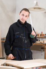 Young carpenter working in his workshop with meter