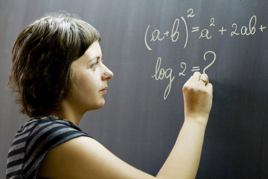 Teacher Writing Math Formulas On Blackboard