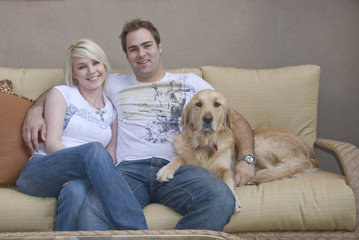 young couple and their dog sitting on sofa
