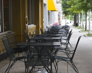 Rows of iron tables on a sidewalk outside a restaurant