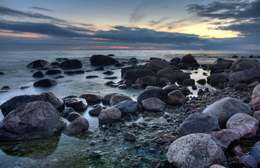 Mysterious view of stones and pebbles in water after sunset.