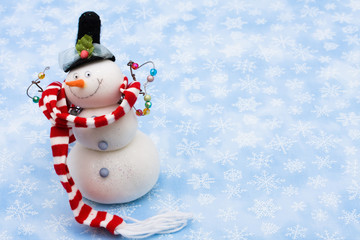 Snowman wearing scarf on blue snowflake background