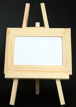 A blank wood framed picture sits on an easel in the horizontal.