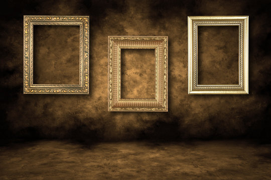 Three Guilded Picture Frames Hanging on a Grungy Wall