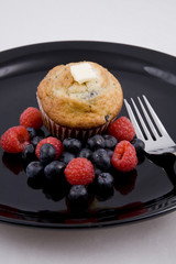Hot muffins & fresh berries on black plate with fork