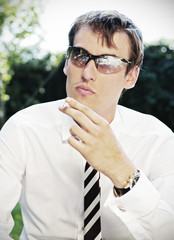 young businessman in sunglasses smoking the cigarette