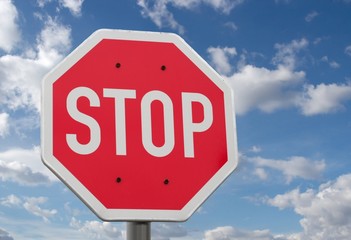 Stop sign against blue sky and clouds