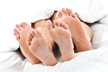 Füße und Zehen von Paar im Bett