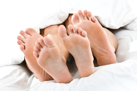 F&uuml;&szlig;e und Zehen von Paar im Bett