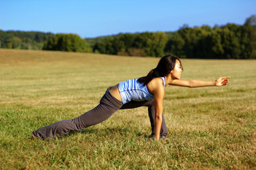 Girl practicing yoga in a summer meadow.