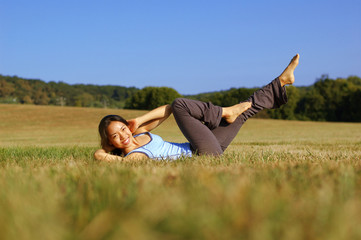 Naklejka na ściany i meble Girl practicing yoga in a summer meadow.