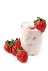 Glass of strawberry yoghurt, surrounded by strawberries.