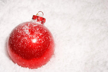 Red Christmas bauble on a bed of snow with copyspace