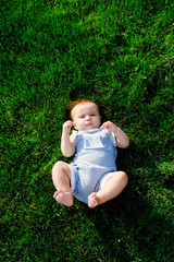 Baby girl lying on the grass and looking into camera