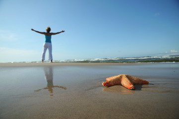 Starfish and tranquil woman on sandy beach