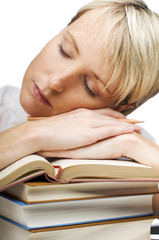 tired young woman sleeping on a stack of books
