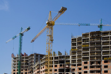 the skyscraper building by three hoisting cranes